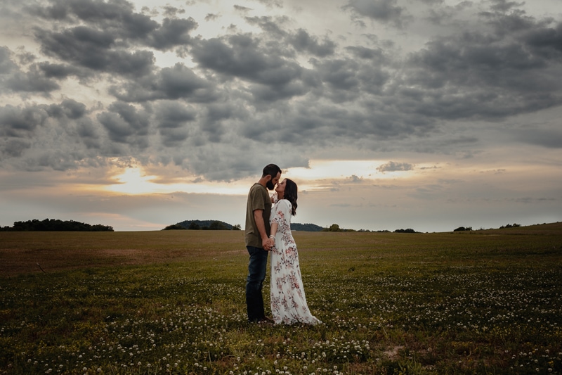 Elopement Photographer, husband and wife kiss in a grassy field at dusk